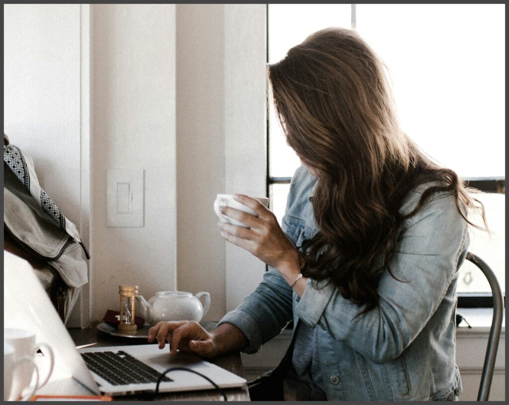 コーヒーを飲みながらパソコンを触る女性